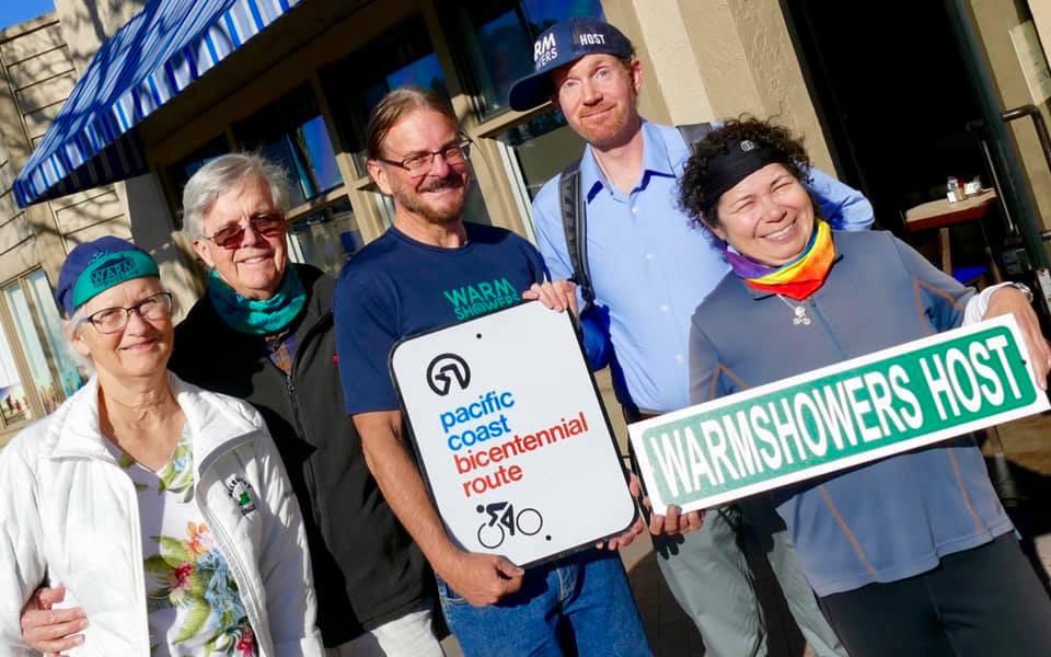 Gruppe von Personen, die ein Warmshowers-Gastgeberschild halten